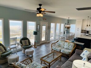 A spacious living area with a large window, a ceiling fan, and a dining area with a view.