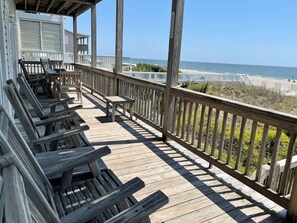 A wooden deck with benches and a table, overlooking a beach.