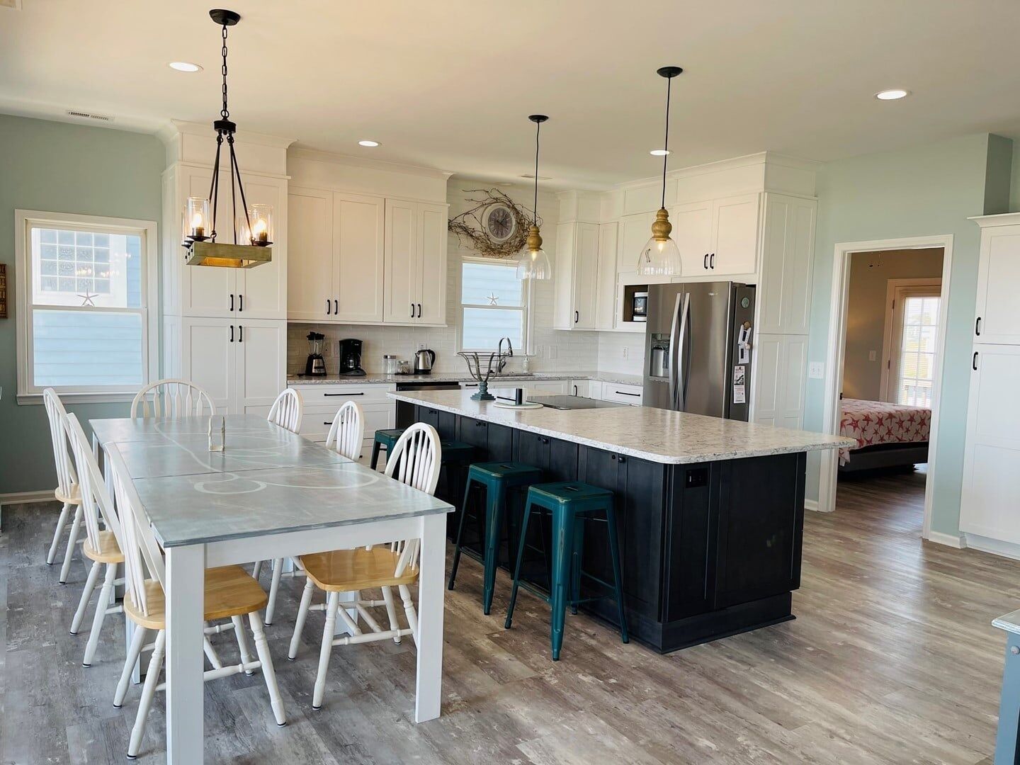 Una cocina moderna con gabinetes blancos, una isla central y taburetes de bar.