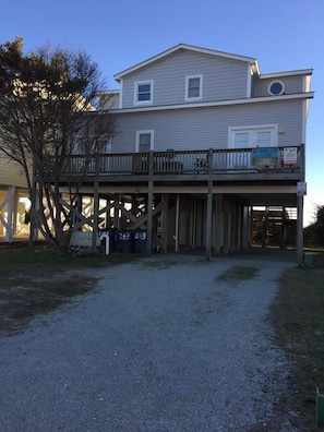 A two-story building with a balcony, a covered area, and a gravel driveway.