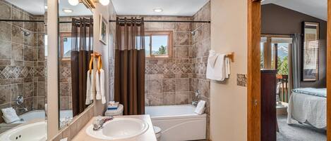 A bathroom with a bathtub, a sink, a mirror, and a shower.