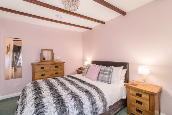 A bedroom with a bed, wooden nightstand, dresser, and a mirror. - Stilworth House (York)
