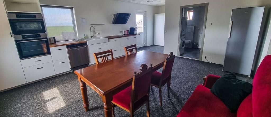 A kitchen with a dining table and chairs, a refrigerator, and a window.