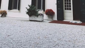 Un bâtiment blanc doté de nombreuses fenêtres et d’une porte, présentant un style architectural traditionnel avec un toit plat et un petit balcon à l’étage supérieur.