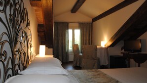 Une chambre d’hôtel avec un lit, une chaise, un téléviseur et une fenêtre avec des rideaux.