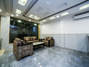 Un espacio lounge moderno con sofás de cuero, suelo de mármol, iluminación empotrada en el techo y un gran ventanal.