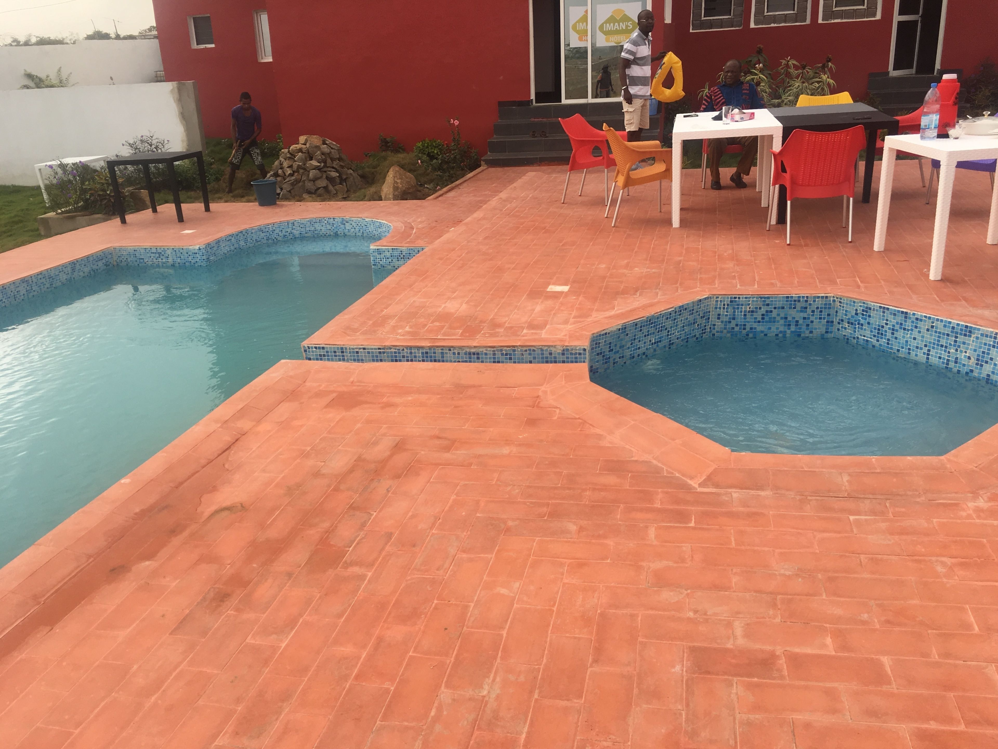 A swimming pool with tiled edges and a patio area with outdoor seating.