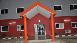 Un bâtiment à la façade rouge, doté d’une entrée en verre et de piliers orange.