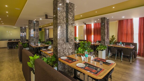Un restaurant avec des piliers de marbre, des tables en bois et des rideaux rouges.