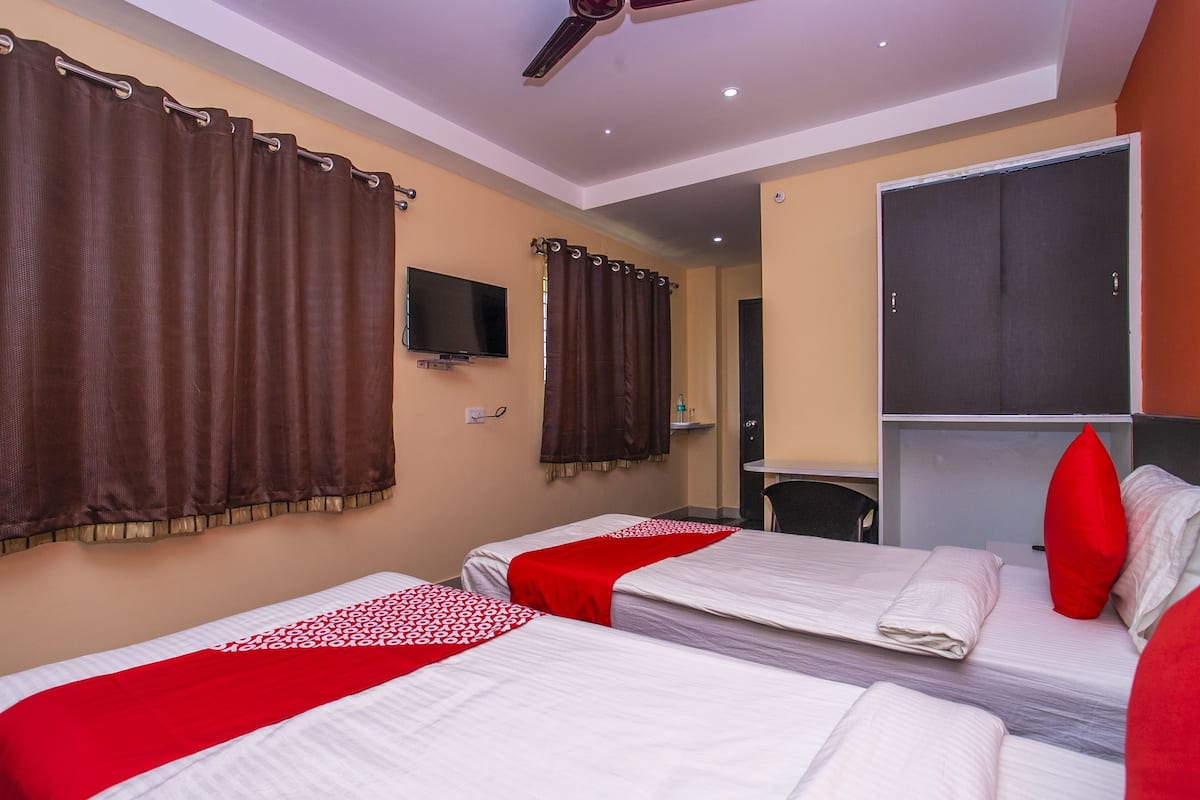 Ein Hotelzimmer mit zwei Betten, einem Deckenventilator, einem Fernseher und einem Kleiderschrank.