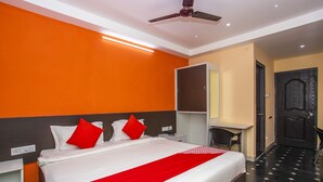Une chambre d’hôtel avec un lit, un bureau, une chaise et une armoire.
