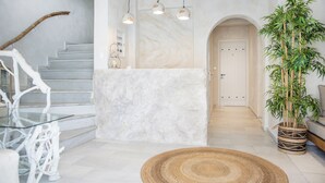 A modern interior with a marble reception desk, a staircase with glass railings, and a large potted bamboo plant. - Terra Fos Naxos Studios (Naxos)