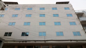A multi-story building with a plain facade, numerous windows, and visible electrical wires. - OYO 24248 Hotel Salt (New Delhi)