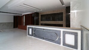 A modern hotel lobby with a reception desk, marble flooring, and a high ceiling with recessed lighting. - OYO 24248 Hotel Salt (New Delhi)