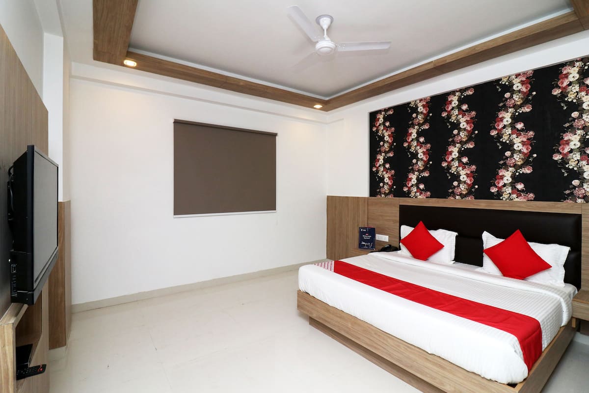 Ein Schlafzimmer mit Bett, Fernseher, Deckenventilator und floralem Wandpapier.