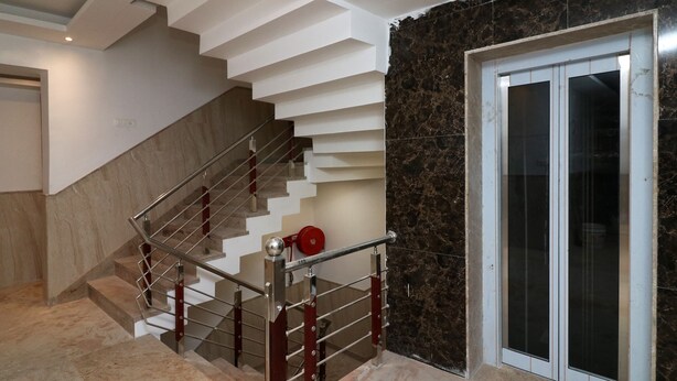 A modern staircase with a metal handrail and red accents, leading to a room with dark marble walls and a sliding glass door. - OYO 24248 Hotel Salt (New Delhi)
