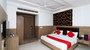 A modern hotel room with a large bed, a desk, a television, and a ceiling fan. - OYO 24248 Hotel Salt (New Delhi)