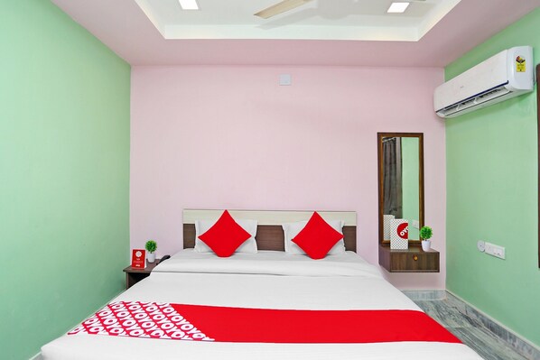 A bedroom with a bed, a nightstand, a mirror, and an air conditioning unit.
