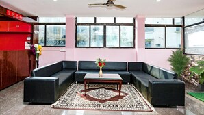Een moderne woonkamer met een hoekbank, een salontafel, een plafondventilator en grote ramen.
