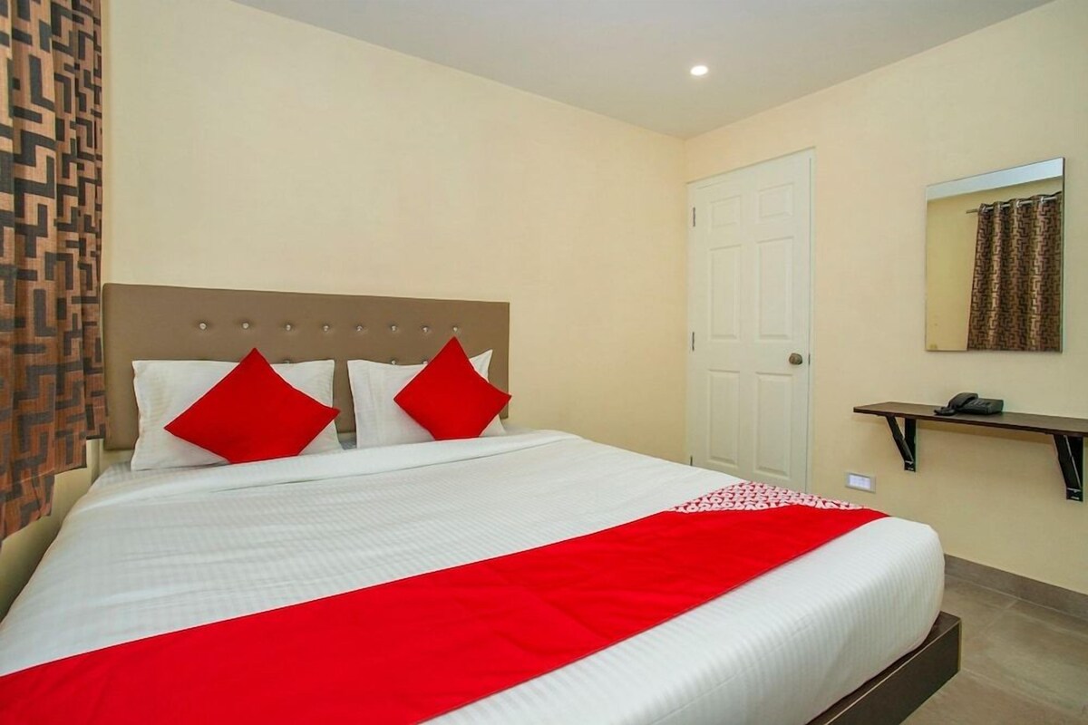 Une chambre d’hôtel avec un lit, une porte, un miroir et une petite étagère.