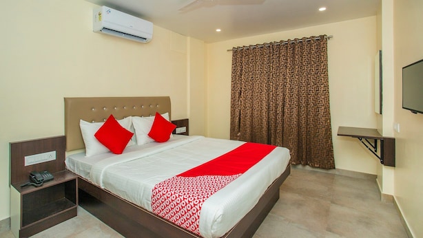 Une chambre d’hôtel équipée d’un lit, d’un ventilateur de plafond, d’un appareil de climatisation, d’une télévision et d’un rideau à motifs.