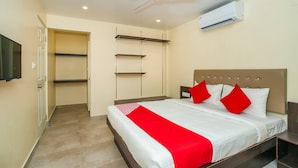 Une chambre à coucher comprenant un lit, un ventilateur de plafond, un appareil de climatisation et un téléviseur fixé au mur.