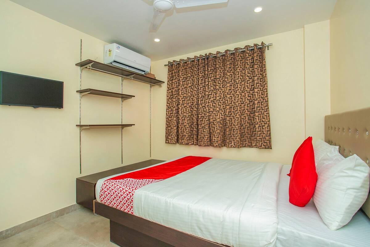 Een slaapkamer met een bed, een aan de muur bevestigde televisie en een airconditioning.