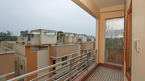 A balcony with a metal railing, a patterned floor, and a view of adjacent buildings. - OYO 16722 The Countryside Resort (Bhubaneshwar)
