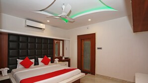 A modern bedroom with a large bed, a ceiling fan, an air conditioning unit, and a wooden door. - OYO 16722 The Countryside Resort (Bhubaneshwar)
