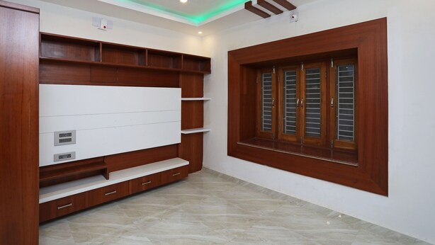 A room with a built-in TV, wooden shelving, a window with shutters, and a recessed ceiling light. - OYO 16722 The Countryside Resort (Bhubaneshwar)