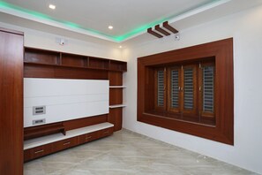 A room with a built-in TV, wooden shelving, a window with shutters, and a recessed ceiling light. - OYO 16722 The Countryside Resort (Bhubaneshwar)