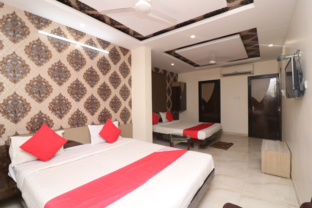 A hotel room with two beds, a TV, and a mirror.