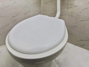 A white toilet with a marble-patterned wall and floor.