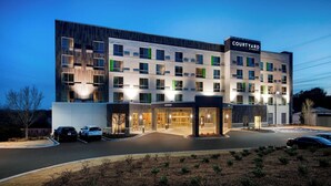 Ein Courtyard Hotel im modernen Stil mit mehreren Etagen, großen Fenstern und einem gut beleuchteten Eingang.