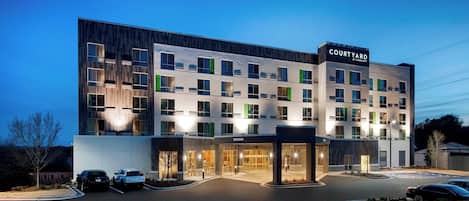 A Courtyard hotel with a modern design, featuring multiple floors, large windows, and a well-lit entrance.