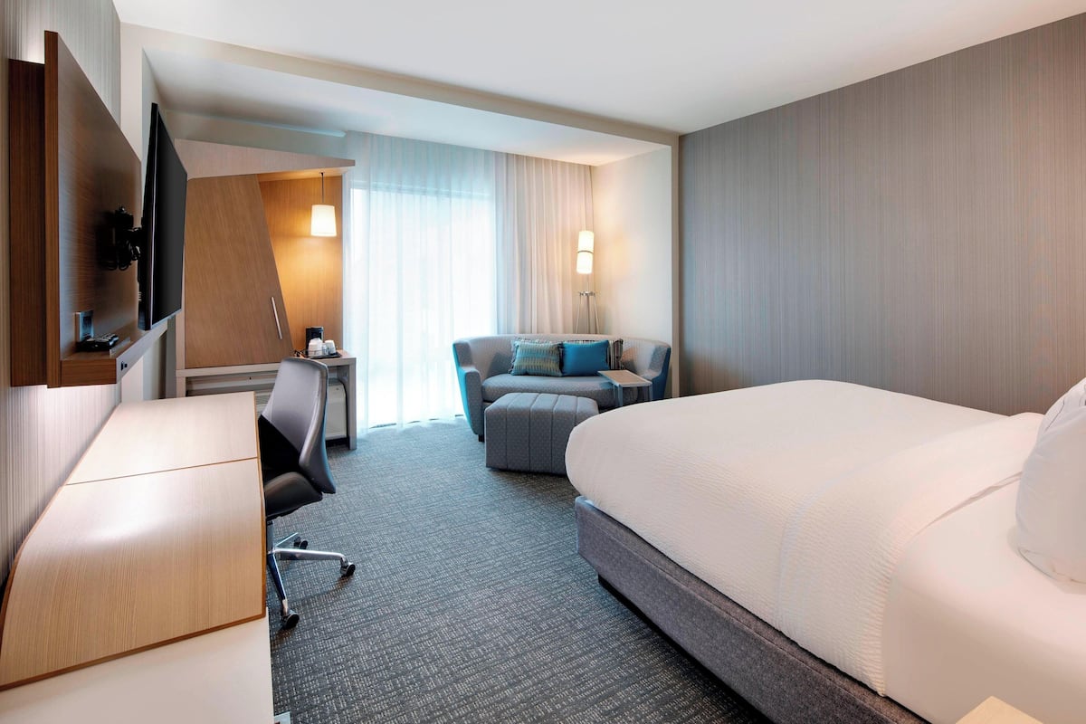 Ein Hotelzimmer mit einem großen Bett, einem Schreibtisch, einem Sofa und einem Fernseher.