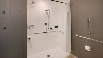 A modern bathroom with a walk-in shower, grab bars, a towel rack, and a toilet paper holder.