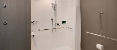 A modern bathroom with a walk-in shower, grab bars, a towel rack, and a toilet paper holder.