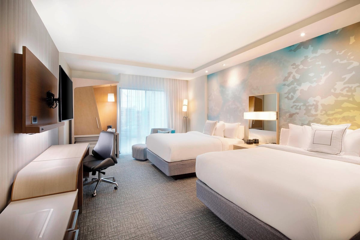 Ein Hotelzimmer mit einem großen Bett, einem Schreibtisch, einem Stuhl, einem Fernseher und einem Badezimmer.