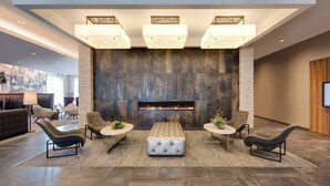 Eine moderne Lobby mit Kamin, Sitzgruppe und großem, an der Wand befestigten Fernseher.