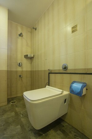 Une salle de bain avec des toilettes blanches, une douche et un sèche-mains.