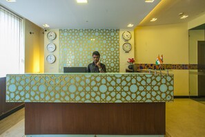 Un comptoir d’accueil avec un décor à motifs, plusieurs horloges et un drapeau indien.