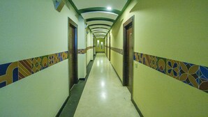 A long, narrow hallway with patterned tile borders and a series of doors on both sides.