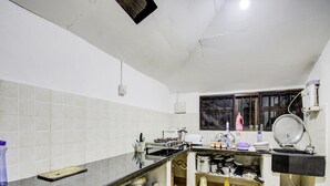 Une cuisine de taille réduite avec des murs recouverts de carreaux blancs, un plan de travail noir et divers appareils de cuisine.