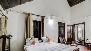 Une chambre à coucher avec un grand lit, une tête de lit en bois, une table de chevet, une lampe et un miroir.