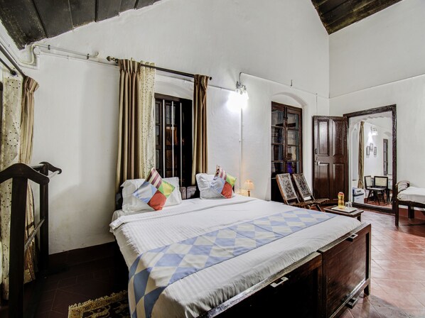 A bedroom with a large bed, a wooden headboard, a nightstand, a lamp, and a mirror.