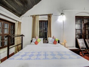 A room with a bed, curtains, a window, and a lamp.
