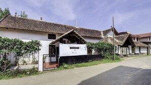 Un bâtiment traditionnel avec un toit en tuiles, une entrée fermée par un portail et un petit jardin.