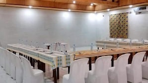A conference room with a long table, white chairs, and a patterned wall.