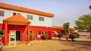 A building with a red and white facade, a covered entrance, and a paved driveway.